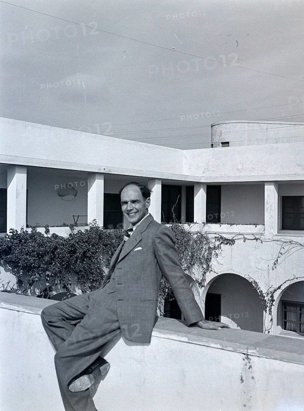 Smartly dressedBritish man sitting on hotel wall of Arabic style building, Tripoli, Libya, North Africa 1956