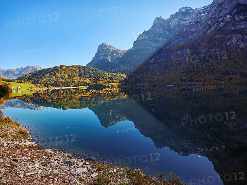 Autumn-colored forest is reflected in Obersee, Näfels, Canton of Glarus, Switzerland
