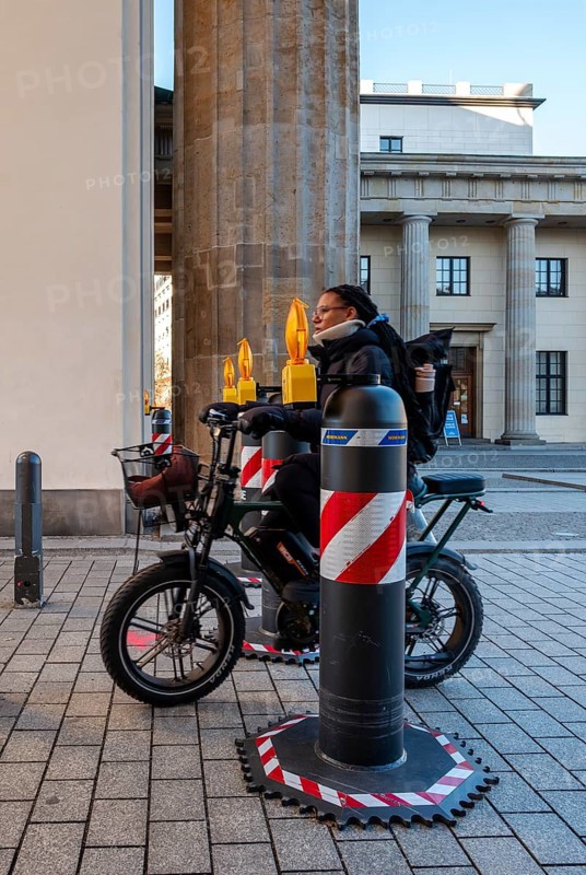 Passers-by at the security barrier made of massive bollards at the Brandenburg Gate passage, Berlin, Germany