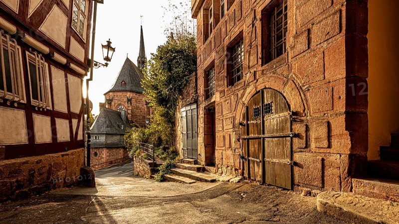 Historic old town alleyway with half-timbered houses and church in the warm light of sunset, The historic alleys and streets of the old town of Marburg