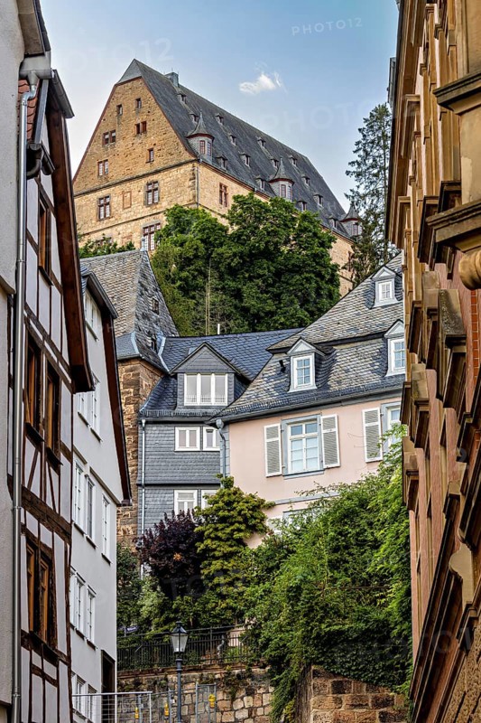 Enge Gasse in Marburg with historic half-timbered and stone buildings under a wooded hill, The Landgrave Castle of Marburg in Hesse