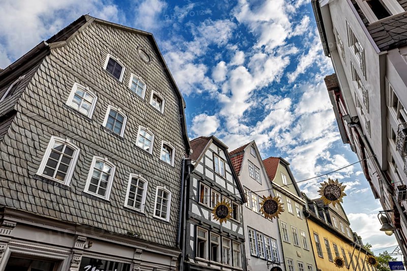 View of half-timbered houses under a vivid blue sky with decorative sun ornaments, The historic old town of Marburg an der Lahn in Hesse