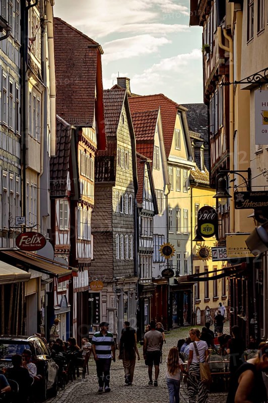 A picturesque old town street with half-timbered houses and walkers in an evening atmosphere, The historic old town of Marburg an der Lahn in Hesse