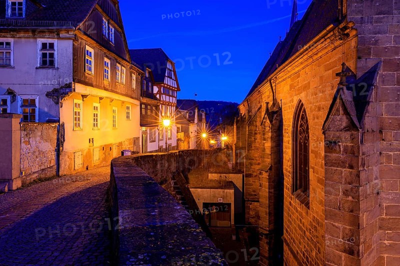 Historic street view at dusk with illuminated half-timbered houses and a church building, At the blue hour in Marburg city center in Hesse