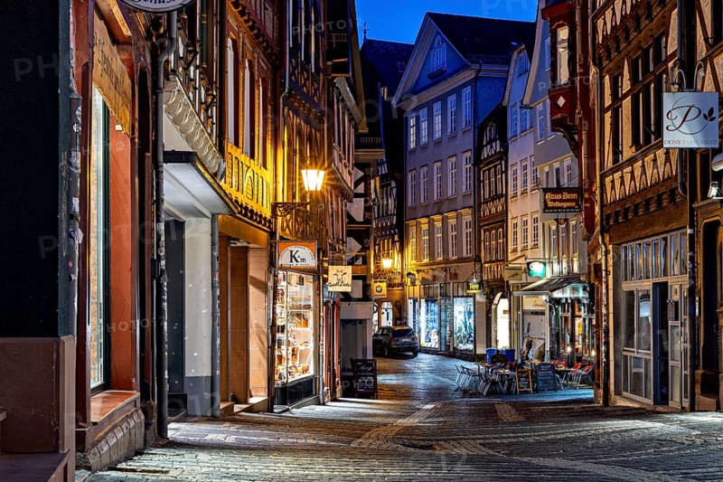 Narrow old town alleyway at night with illuminated shops and historic half-timbered buildings, At the blue hour in Marburg city center in Hesse