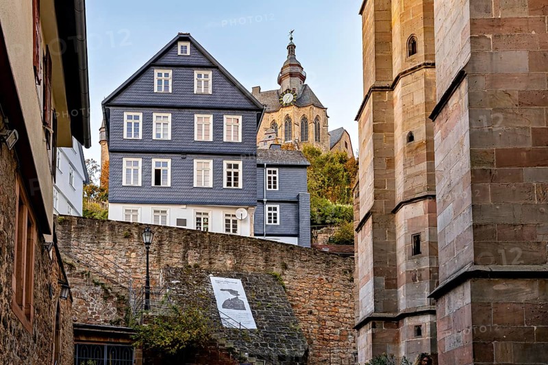 Church over historic city walls in warm evening light, The historic city center of Marburg in Hesse