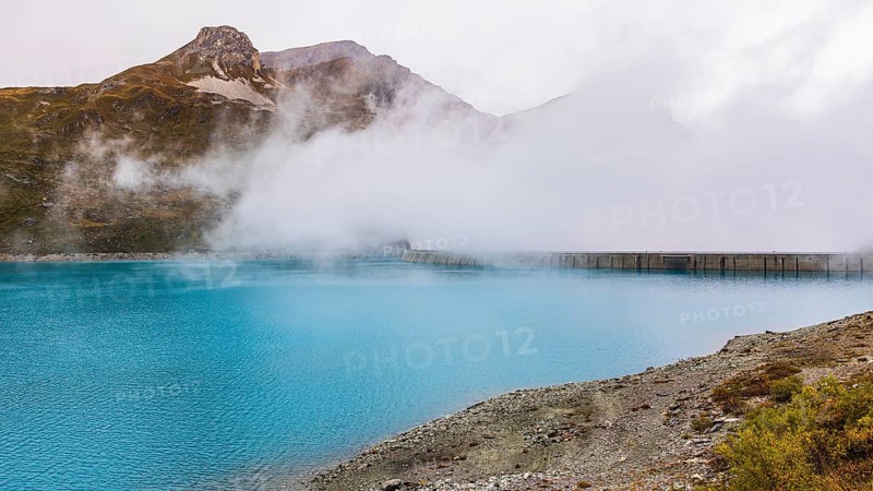 Fog rises over the dam of the Lac de Moiry Reservoir, Val d'Anniviers, Valais Alps, Canton of Valais, Switzerland