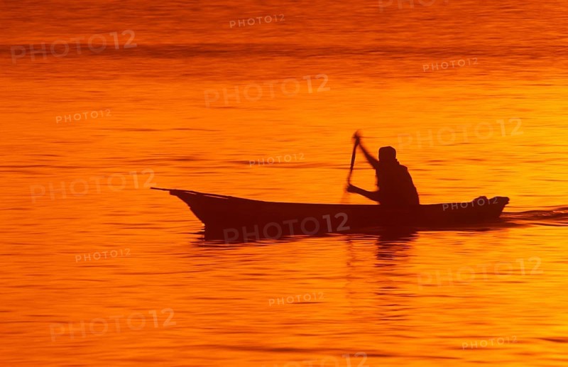 Silhouette of a fisherman in his boat at sunrise near Mikadi Beach, Dar es-Salaam, Tanzania, Africa, June 2000, vintage, retro, old, historic