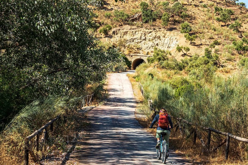 Woman riding a bycicle, cycle path Via Verde de la Sierra, path leads through a tunnel, Puerto Serrano to Olvera, near village Olvera, Andalusia, Spain