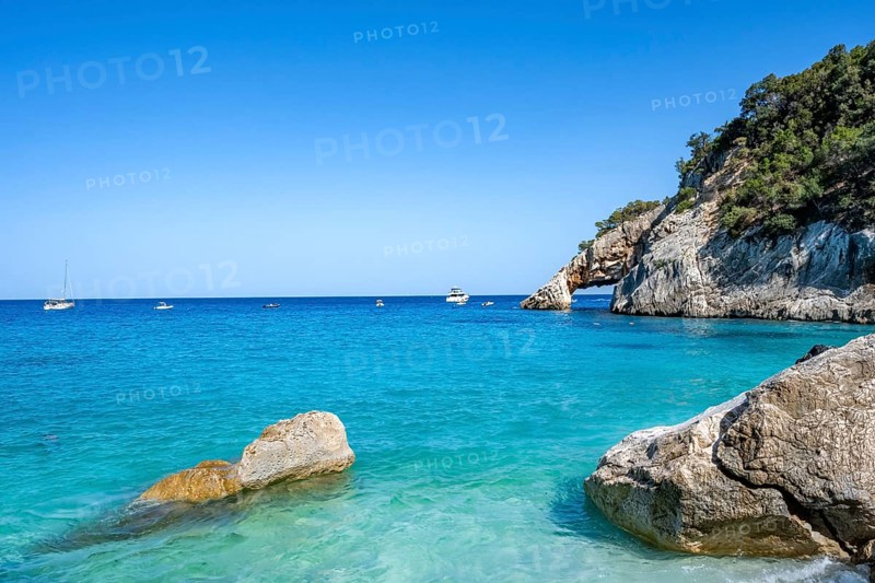 Light blue clear sea on a dream beach on Cala Goloritzé, picturesque rocky coast, cliffs with rock arch, Golfo di Orosei, Baunei, Sardinia, Italy