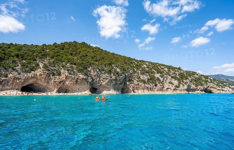 Kayakers in clear blue water, picturesque rocky coast, cliffs and Cala Luna beach, Golfo di Orosei, Baunei, Sardinia, Italy