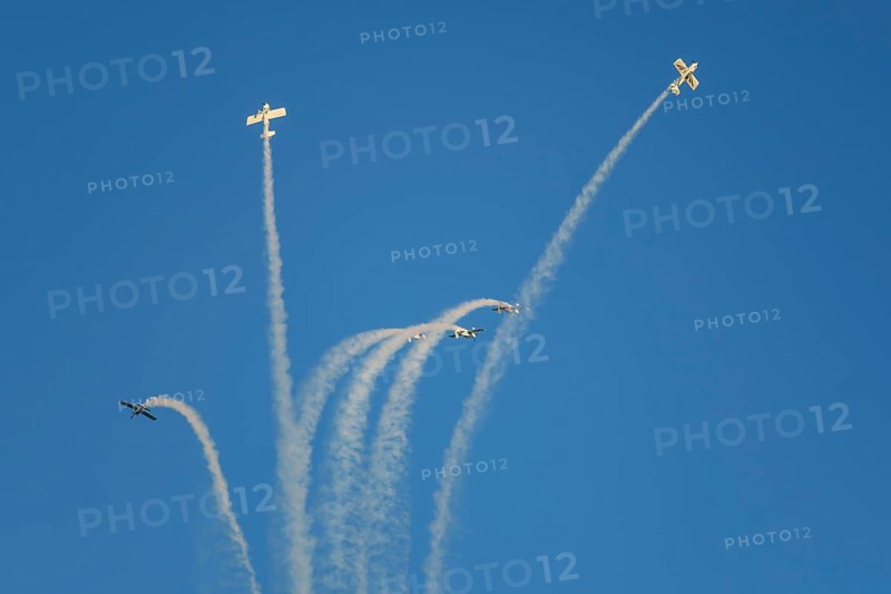 Stunt aerobatic planes performing stunts in blue sky with smoke trail. Concept of teamwork, collaboration, coordination, trust, precision, difficulty, challenge, speed, synergy