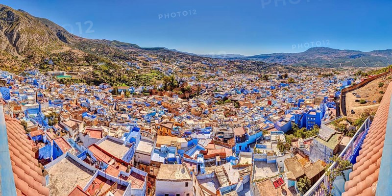View of a city full of blue buildings with mountains in the background, Morocco, Chefchaouen, panorama