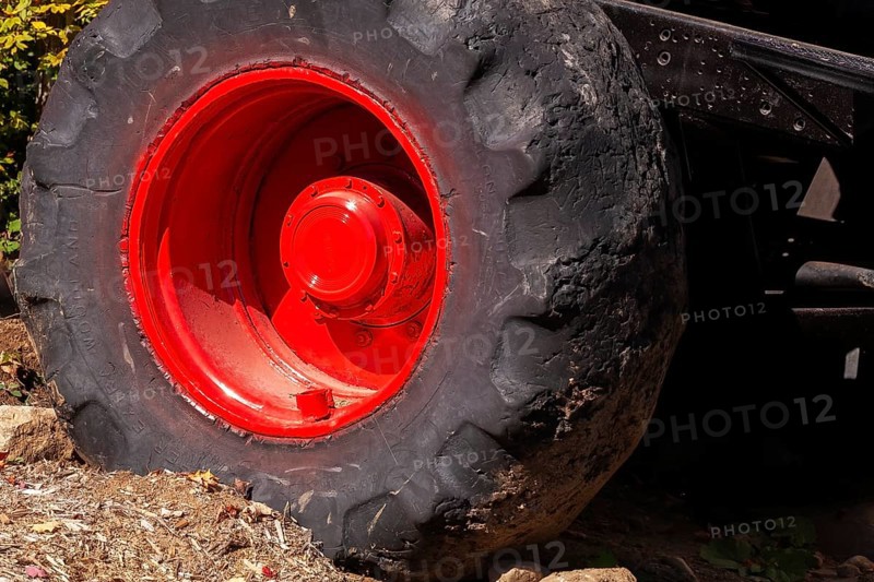 Close-up and rear side view of large heavy duty black rubber tire mounted on red rim on monster truck vehicle, Quebec, Canada