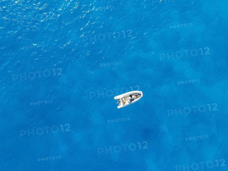 Young woman and young man lying in a motor boat on a blue sea, top-down, aerial view, Golfo di Orosei, Baunei, Sardinia, Italy
