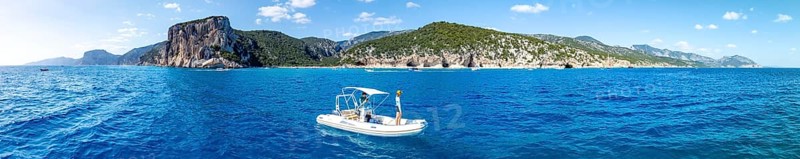Motor boat off picturesque rocky coast, cliffs and Cala Luna beach, aerial view, Golfo di Orosei, Baunei, Sardinia, Italy