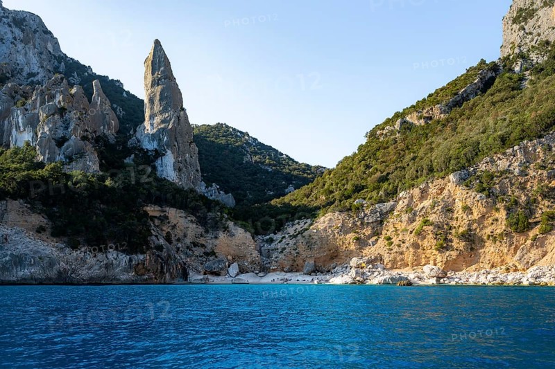 Picturesque rocky coast, cliffs with caves in the morning light, L'Aguglia rock peak, blue sea and Cala Goloritzé beach, Golfo di Orosei, Baunei, Sardinia, Italy
