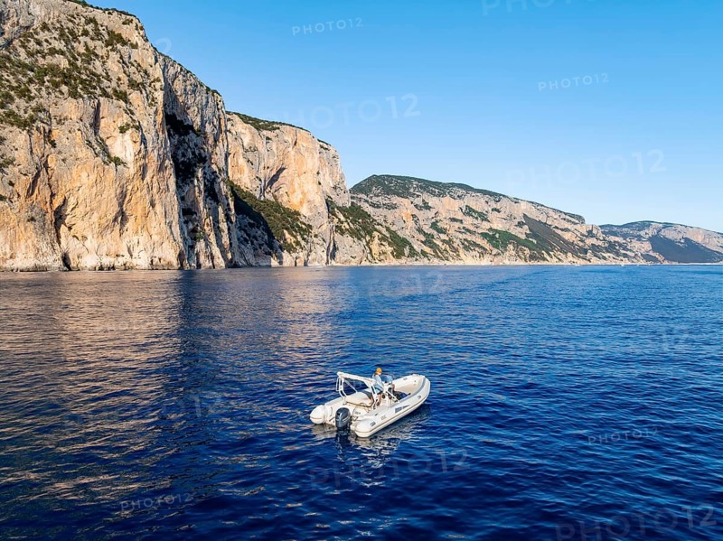 Motorboat off picturesque rocky coast ImmorgenLicht, cliffs, Golfo di Orosei, Baunei, Sardinia, Italy