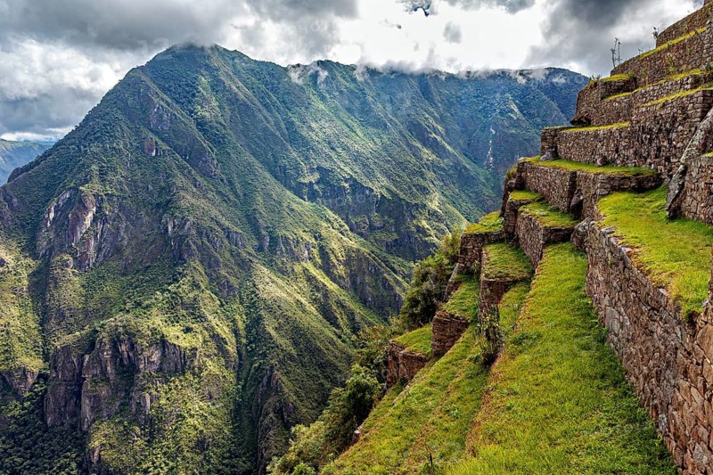 Stone terraces along a slope with spectacular panoramic views of the green mountains, the ruins of the Inca city of Machu Picchu in Peru