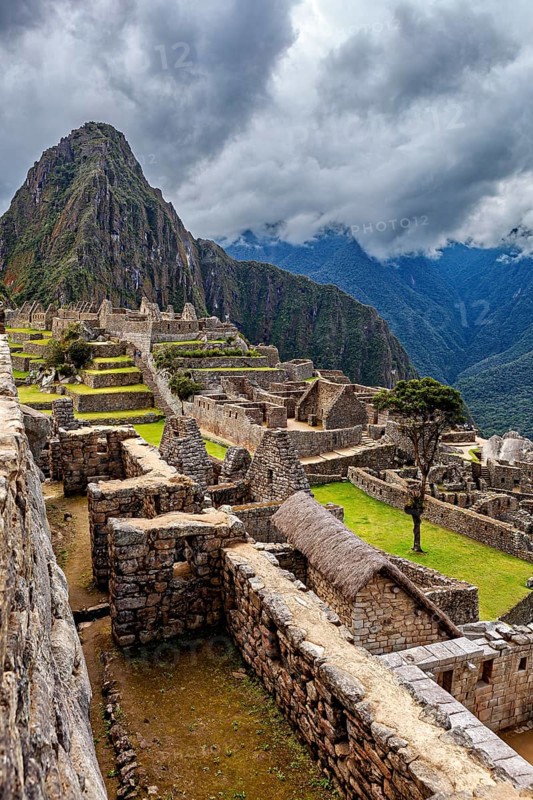 View of the ruined city of Machu Picchu with surrounding Andes and cloudy sky, The ruins of the Inca city of Machu Picchu in Peru