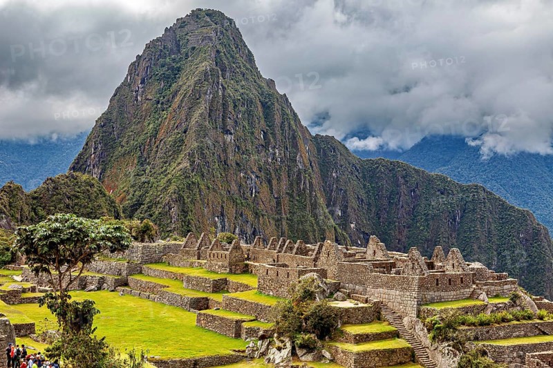 Majestic mountain behind ancient ruins under thick grass and clouds, The ruins of the Inca city of Machu Picchu in Peru