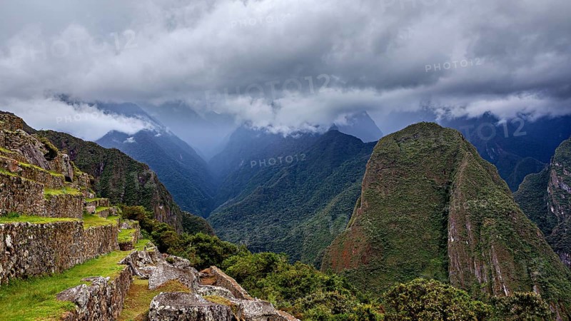 Dramatic mountain landscape with clouds and lush greenery interspersed with fog, The ruins of the Inca city of Machu Picchu in Peru