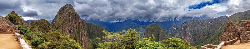 Panoramic view of dramatic mountains and wooded slopes under a cloudy sky near Machu Picchu, The ruins of the Inca city of Machu Picchu in Peru