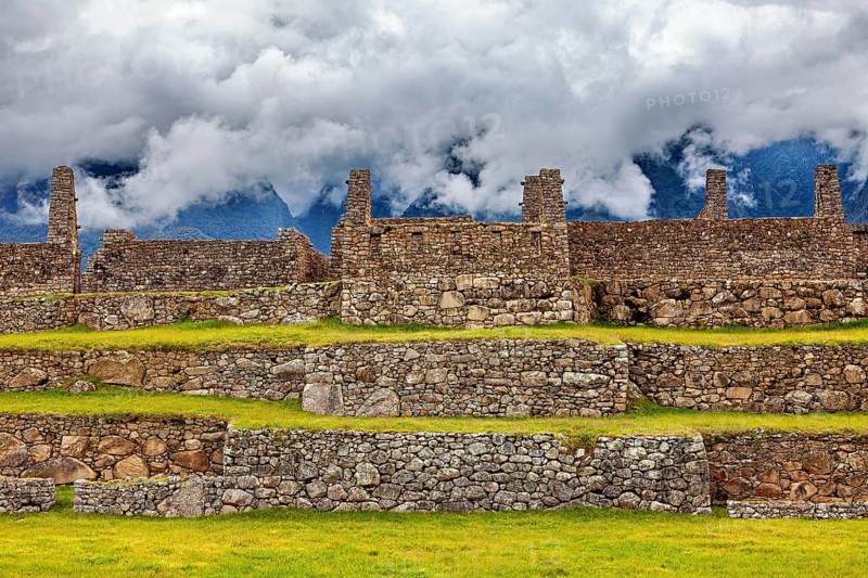 Stone ruins on several levels with mountains and clouds in the background, The ruins of the Inca city of Machu Picchu in Peru