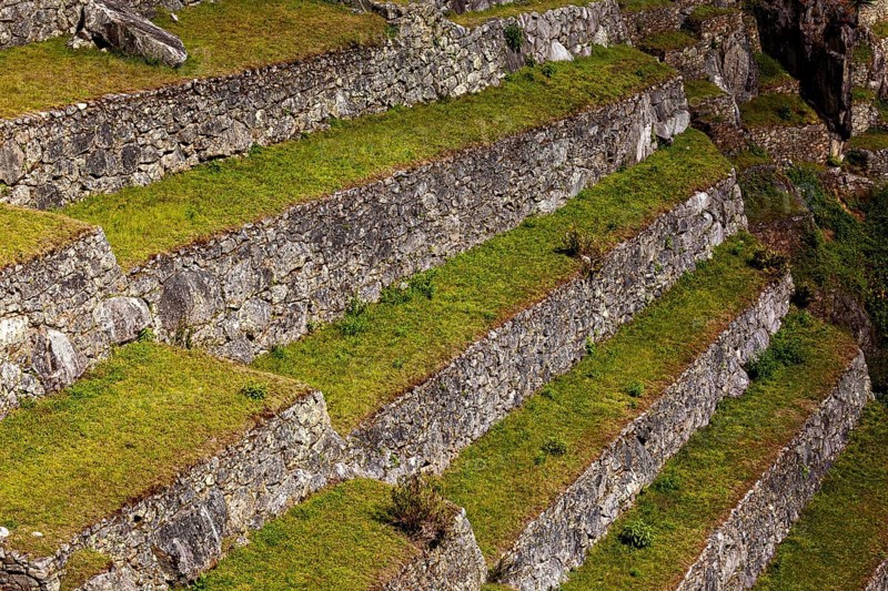 Close-up of hard stone terraces with grassy steps, The ruins of the Inca city of Machu Picchu in Peru