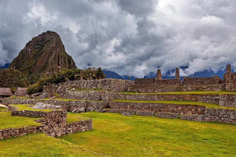 Ancient ruins against a dramatic sky with dark clouds and green areas, The ruins of the Inca city of Machu Picchu in Peru
