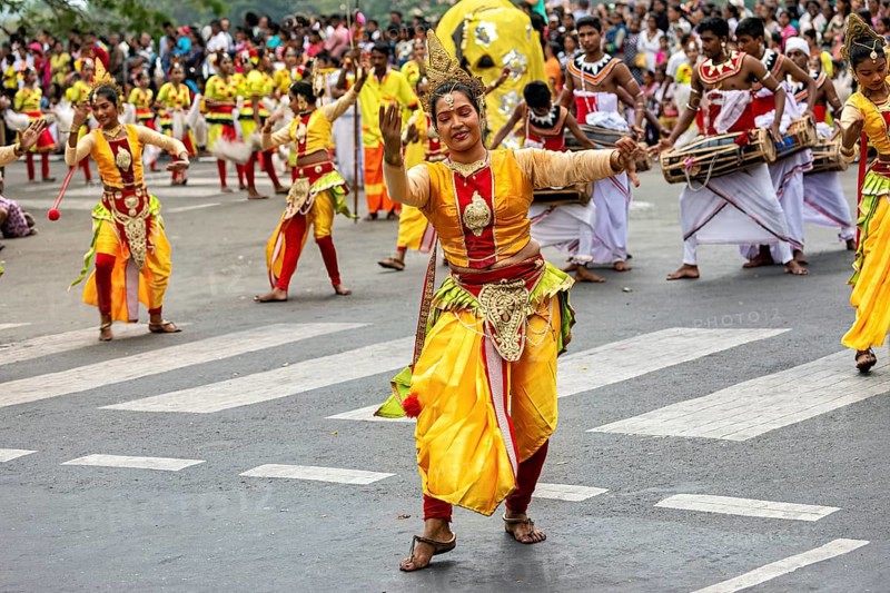 Woman in glowing traditional costume dances joyfully at a cultural parade, The Perahera Parade in Kandy Sri Lanka