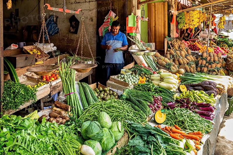 A variety of fresh vegetables on a busy market stand, dealers in the market halls of Kandy Sri Lanka