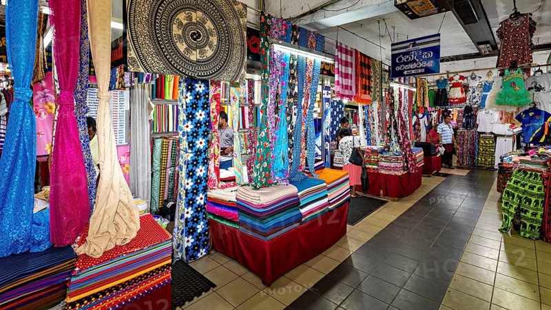 Various colorful fabrics and textiles are on display in a busy market hall, dealers in the market halls of Kandy Sri Lanka