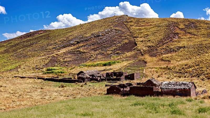 Ruins on a hill in a grassy landscape under a cloudy sky, The landscape in the highlands of Peru