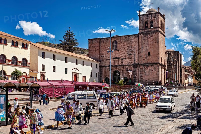 Street scene in a city with a church and people in traditional costumes, traditional parade of festival groups in Cusco in Peru