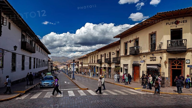 Busy street in a city with colonial architecture under a cloudy sky, The streets of Cusco in Peru