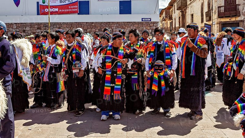 People wearing traditional clothes wearing colorful scarves take part in a street parade, traditional parade of festival groups in Cusco in Peru