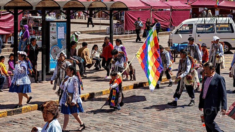 People wearing traditional clothes with colorful flags on a street, traditional parade of festival groups in Cusco in Peru