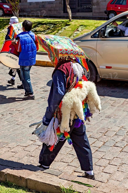 Person with traditional robe and colorful headdress on a street, traditional parade of festival groups in Cusco in Peru
