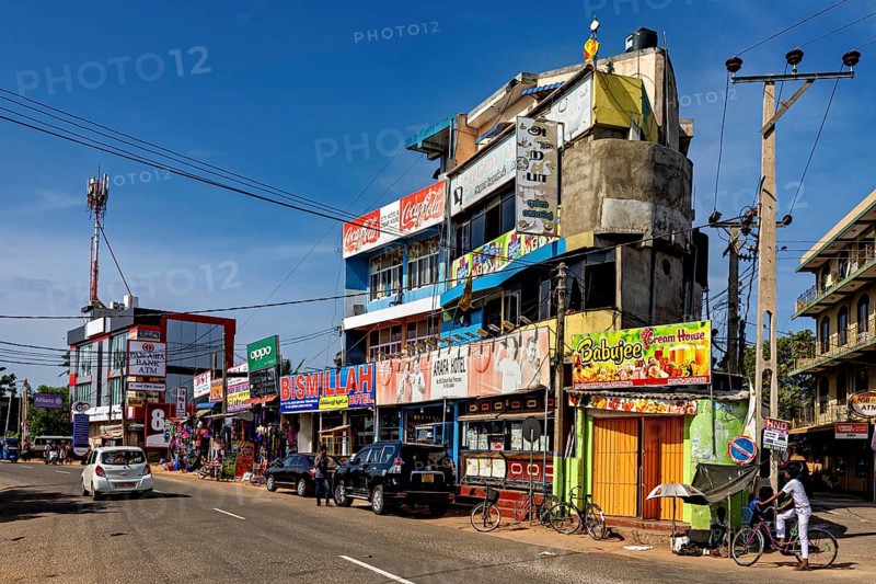 Busy urban street with shops and advertising signs under clear skies, the city of Trincomalee in Sri Lanka