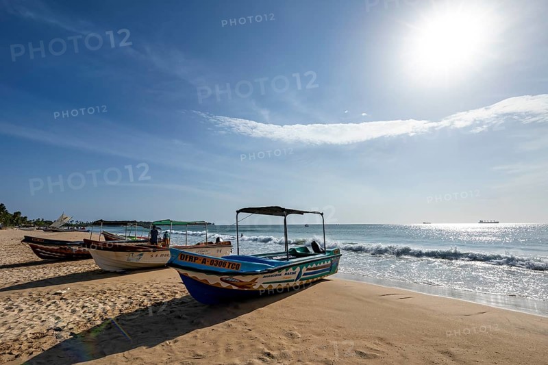 Boats are moored on a sunny beach with soft waves and clear skies, a peaceful atmosphere, Trincomalee beach in Sri Lanka