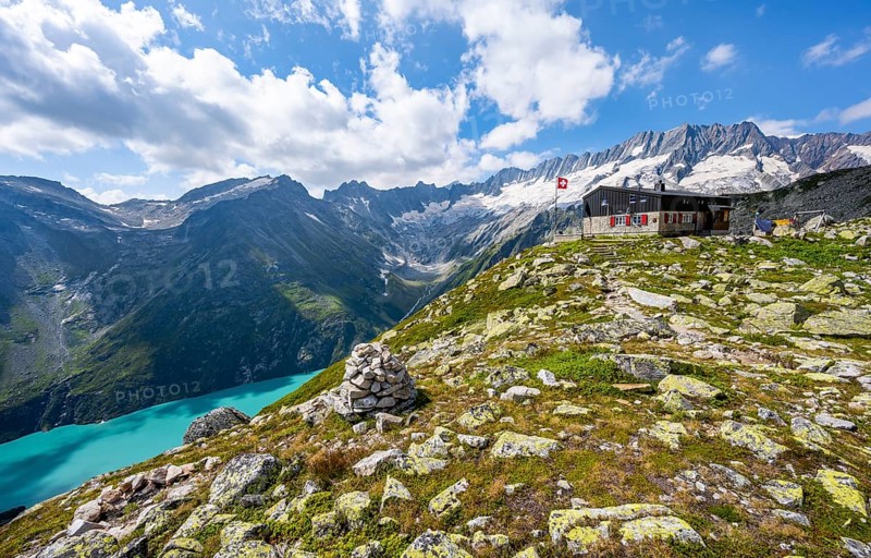 Mountain hut Bergseehütte with Swiss flag in picturesque mountain landscape, view of Damma Glacier and Dammastock, Göscheneralp, Canton of Uri, Switzerland