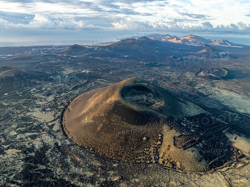 Montaña Negra volcano, picturesque volcanic landscape with volcanic craters and lava fields in morning light, Parque Natural de Los Volcanes, aerial view, Lanzarote, Canary Islands, Spain