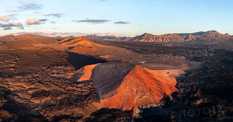 Picturesque volcanic landscape in evening light, red volcano Montaña Bermeja between lava fields, aerial view, Lanzarote, Canary Islands, Spain