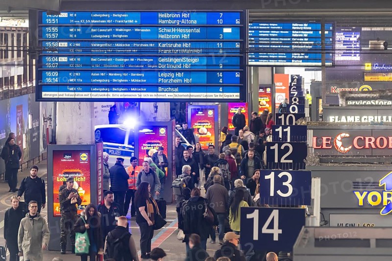 Travelers at the main train station, passengers and departure board at Stuttgart main station. Police vehicle with flashing lights. Stuttgart, Baden-Württemberg, Germany