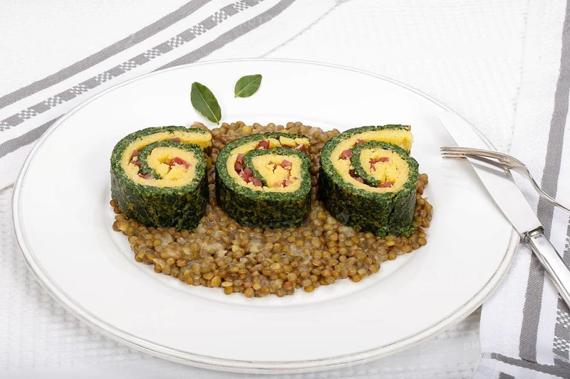 Southern German cuisine, polenta spinach roulade with alblentils served on serving platter, bay leaves, lentil vegetables, smoked meat, bacon cubes, healthy, food photography, studio, Germany