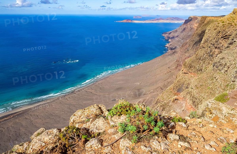 View from the Castillejo viewpoint from the Risco de Famara cliffs to the coast and the sea with the Famara beach, Playa de Famara, Lanzarote, Canary Islands, Spain