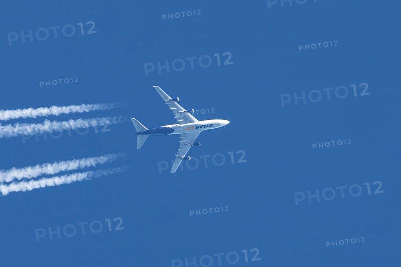 Boeing 747 jumbo jet cargo aircraft of Atlas air airlines flying in a blue sky with contrails or vapour trails behind, England, United Kingdom