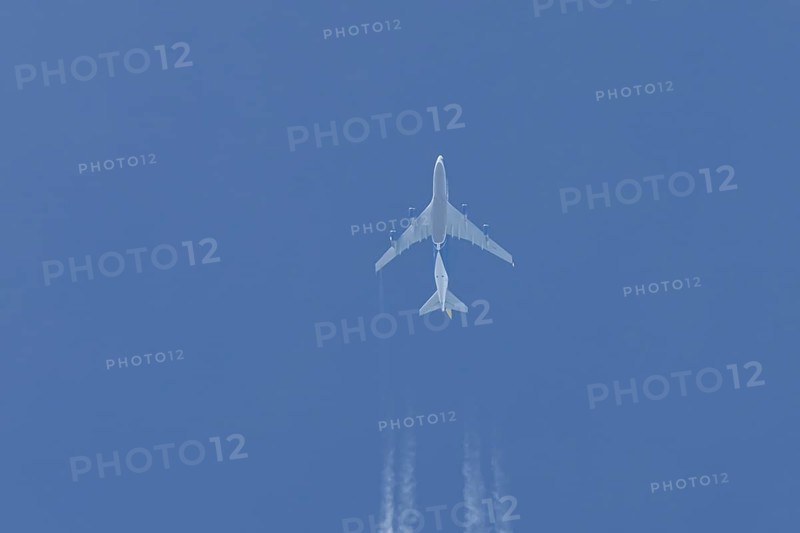 Boeing 747 jumbo jet cargo aircraft flying in a blue sky with contrails or vapour trails behind, England, United Kingdom