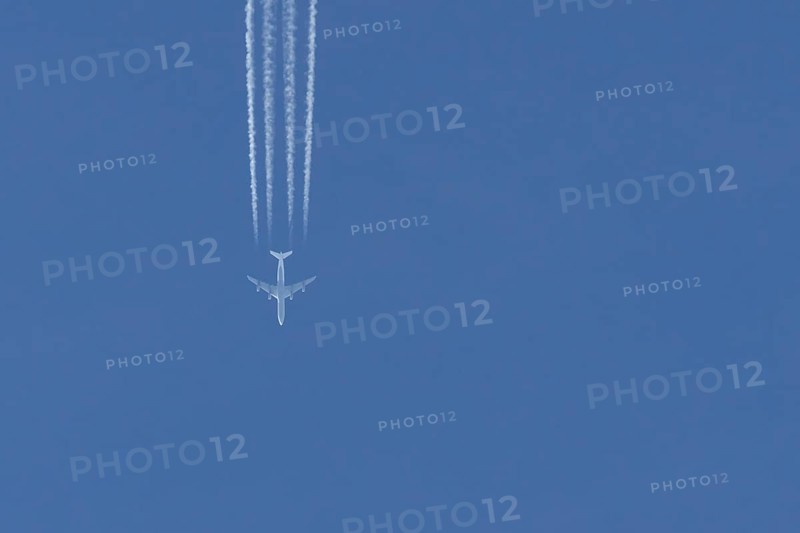 Jet passenger aircraft flying in a blue sky with contrails or vapour trails behind, England, United Kingdom